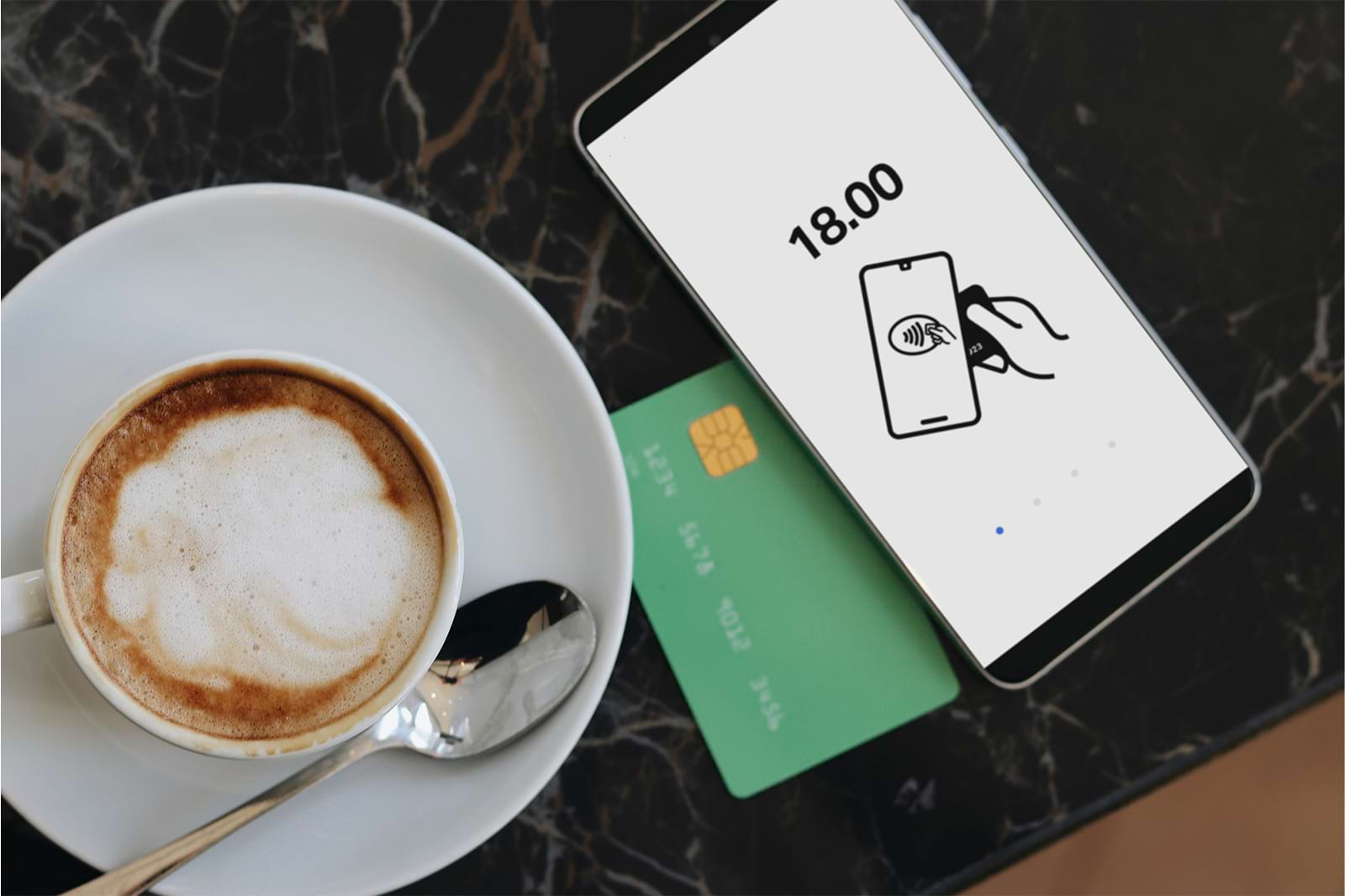 Credit card sitting under a phone next to a coffee cup
