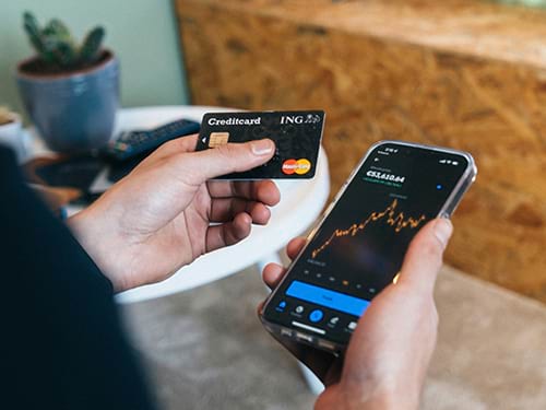Person holding a Mastercard credit card next to their phone