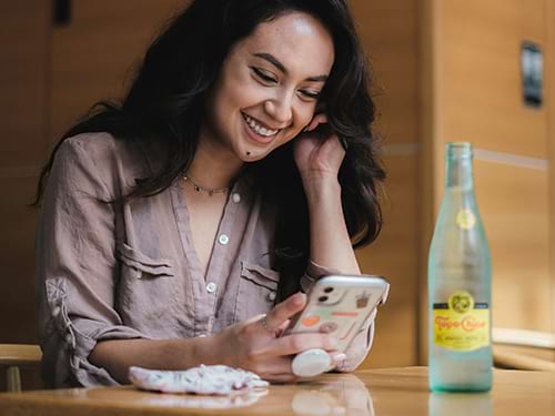 A lady smiling while looking at her phone, accessing online