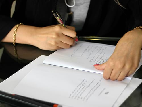 A well-dressed lady signing a financial document