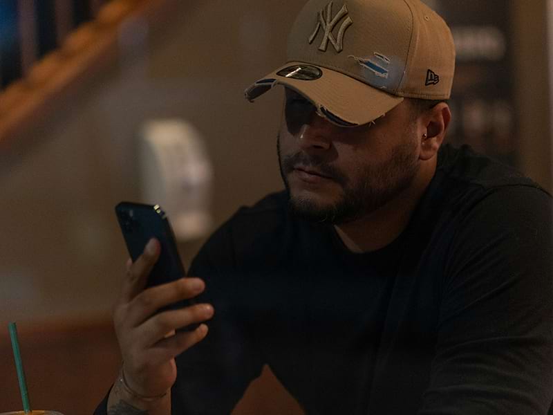 Man with a ballcap using his phone to access an app