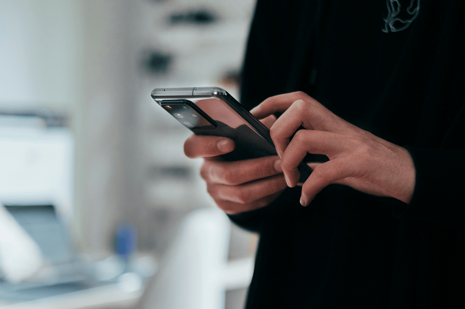 Person in a black long sleeve shirt scrolling on their mobile phone