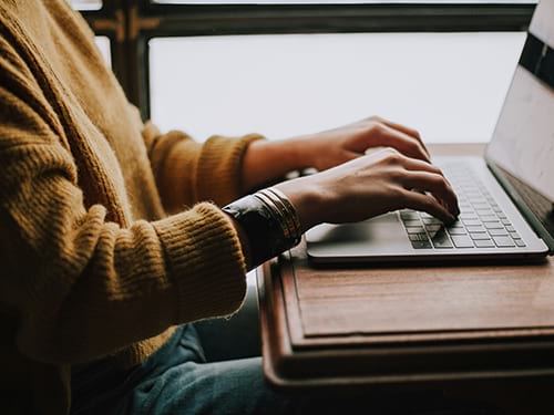 A warmly dressed person accessing the internet on their computer
