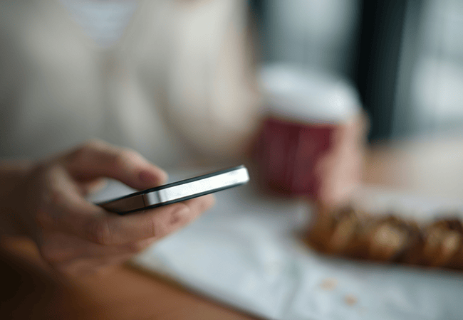 Person using their phone in front of a blurred background
