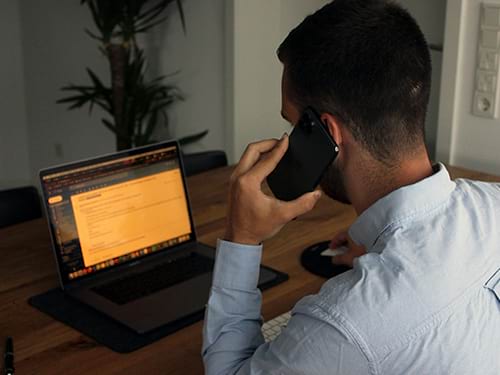 Man on an important phone call with his email pulled up on his computer