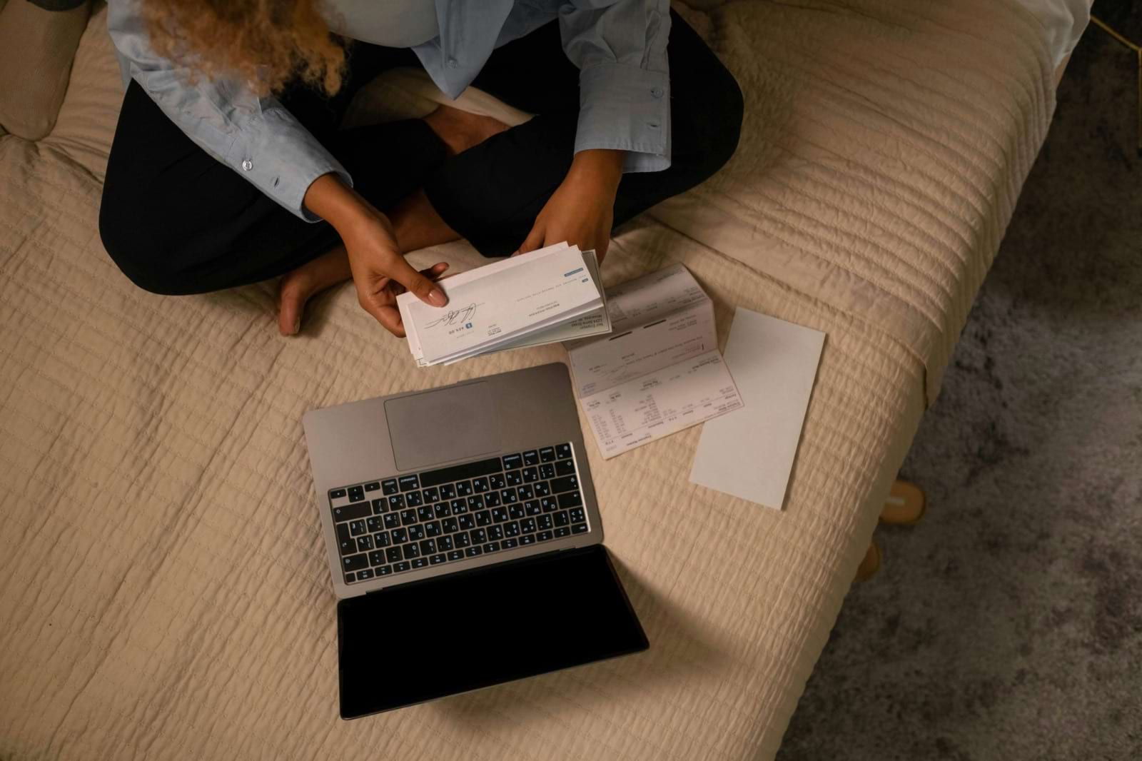 lady sitting on bed with checks and papers