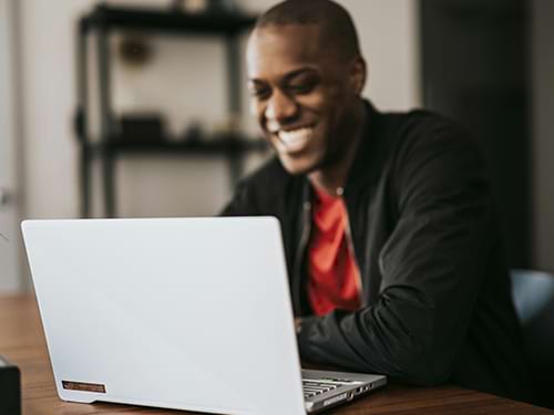 A man smiling as he gets on his computer