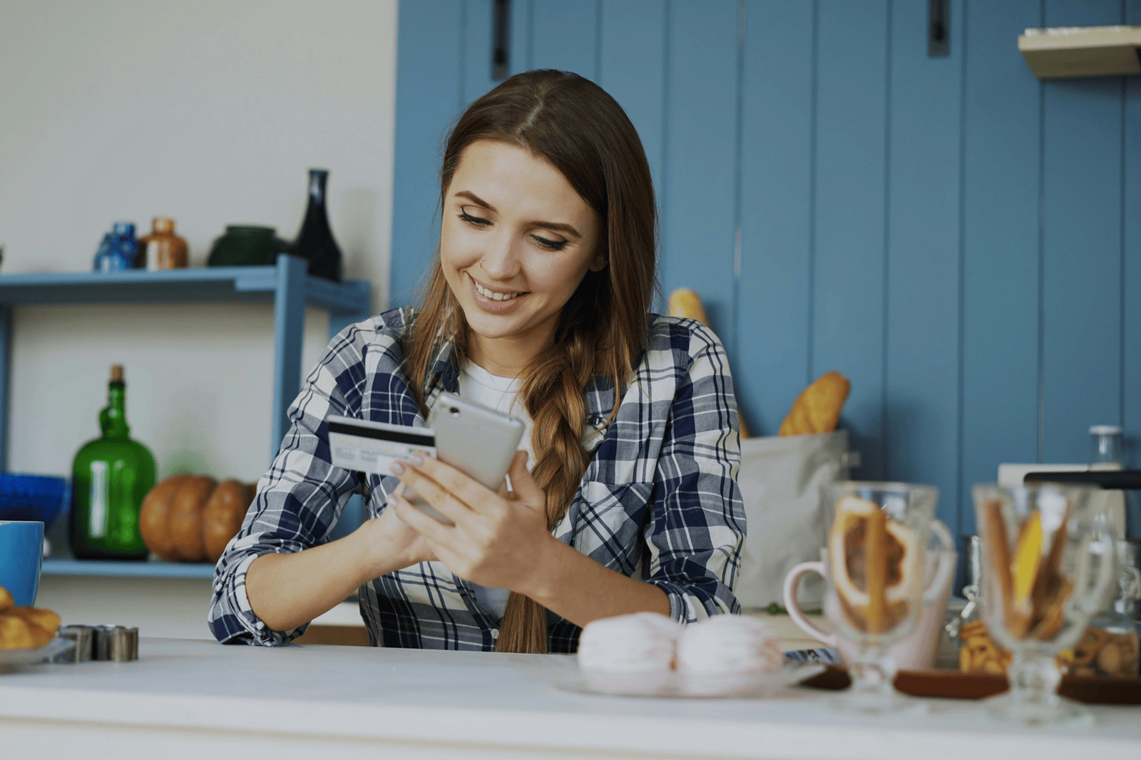 Lady holding her phone and credit card while smiling and placing an order